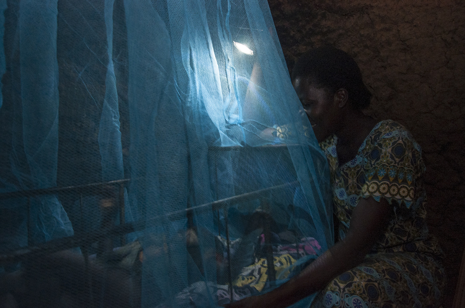 A mother tucks her child under an insecticide-treated mosquito net, a frontline malaria-prevention measure in Kenya