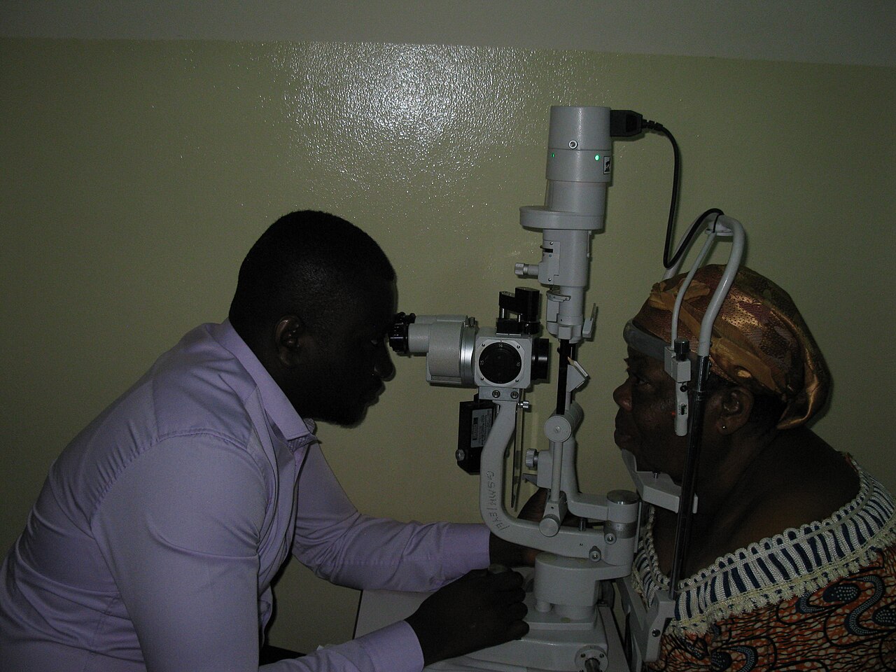 An optometrist performing a slit-lamp eye examination on a patient